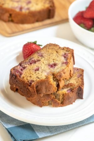 Two pieces of strawberry banana bread stacked on a white plate.