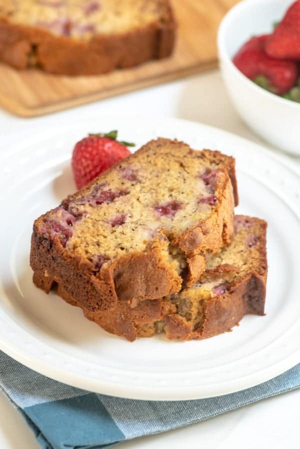 Two pieces of strawberry banana bread stacked on a white plate.