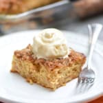 A piece of cake topped with whipped cream on a plate.
