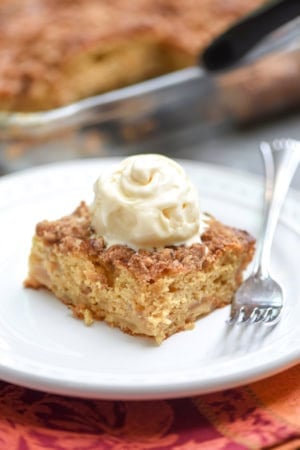 A piece of cake topped with whipped cream on a plate.