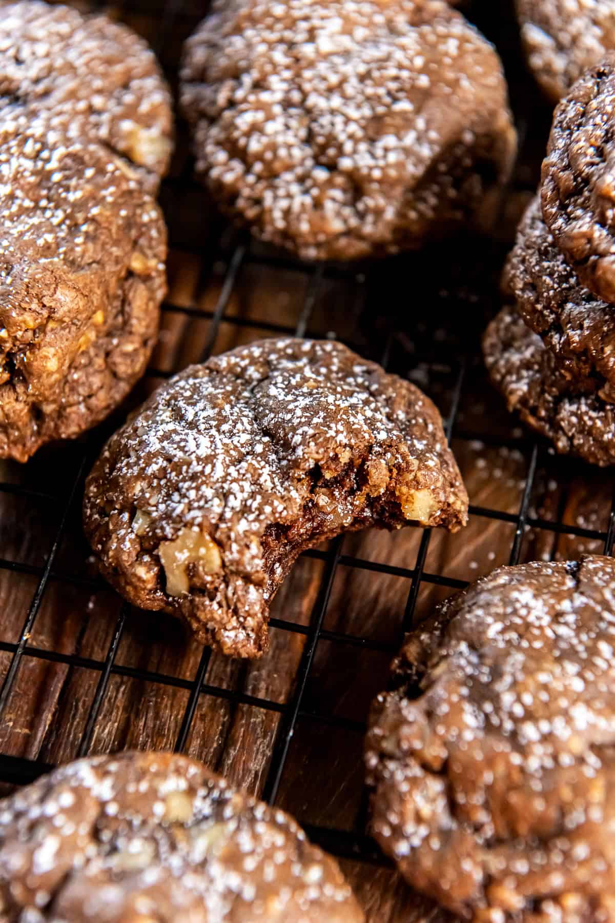 Chocolate Oatmeal Cookies 2 Chocolate oatmeal cookies dusted with powdered sugar on a wire rack with a bite missing from the one in the center.