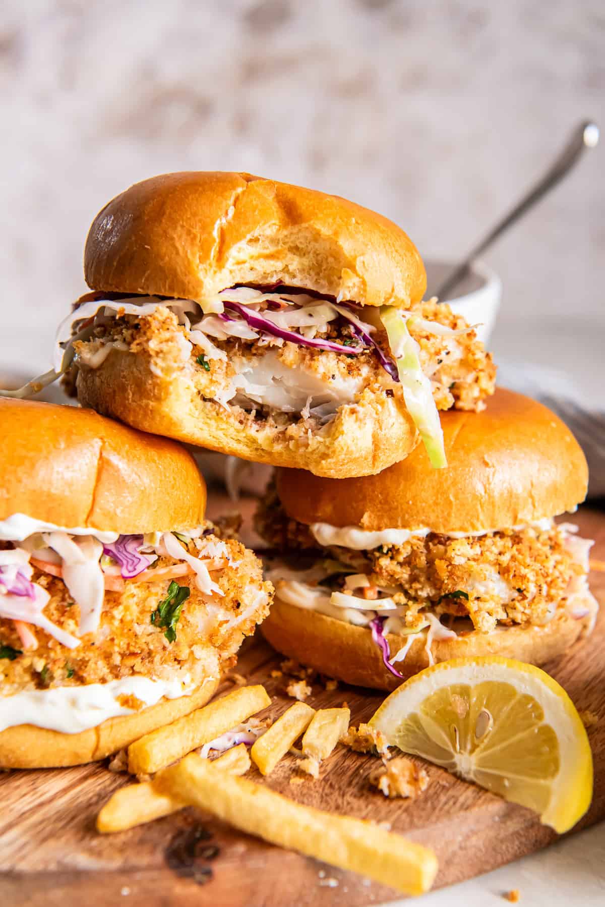 A fish sandwich with a bite missing stacked on two others.