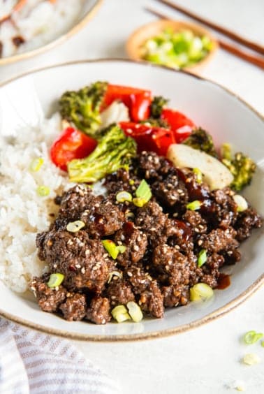 Korean ground beef in a white bowl with rice and roasted vegetables.
