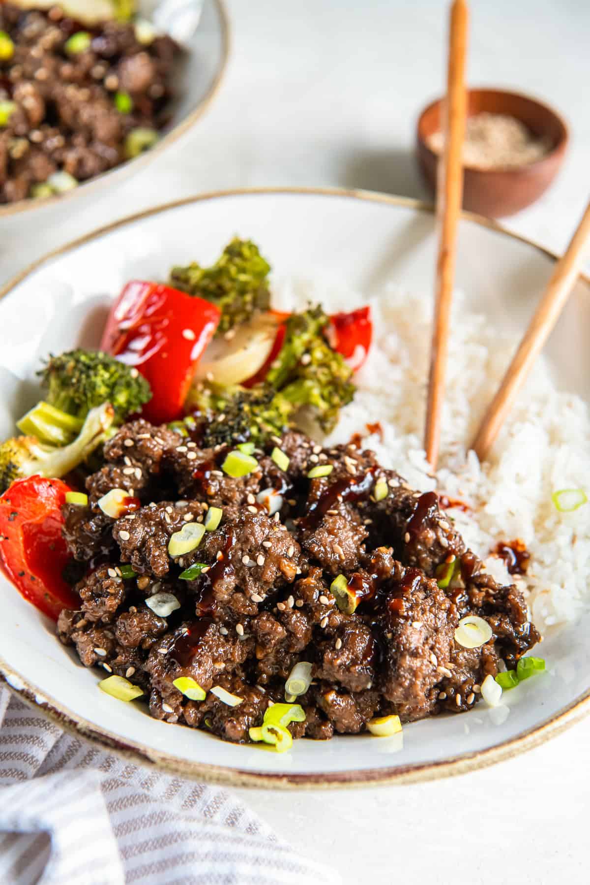 Rest in a Korean ground beef bowl with rice, swayed broccoli and a pillpper.