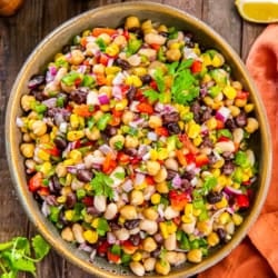 Mexican Bean Salad 7 Mexican bean salad with three types of beans, corn, and bell peppers in a large wood bowl next to an orange kitchen cloth.