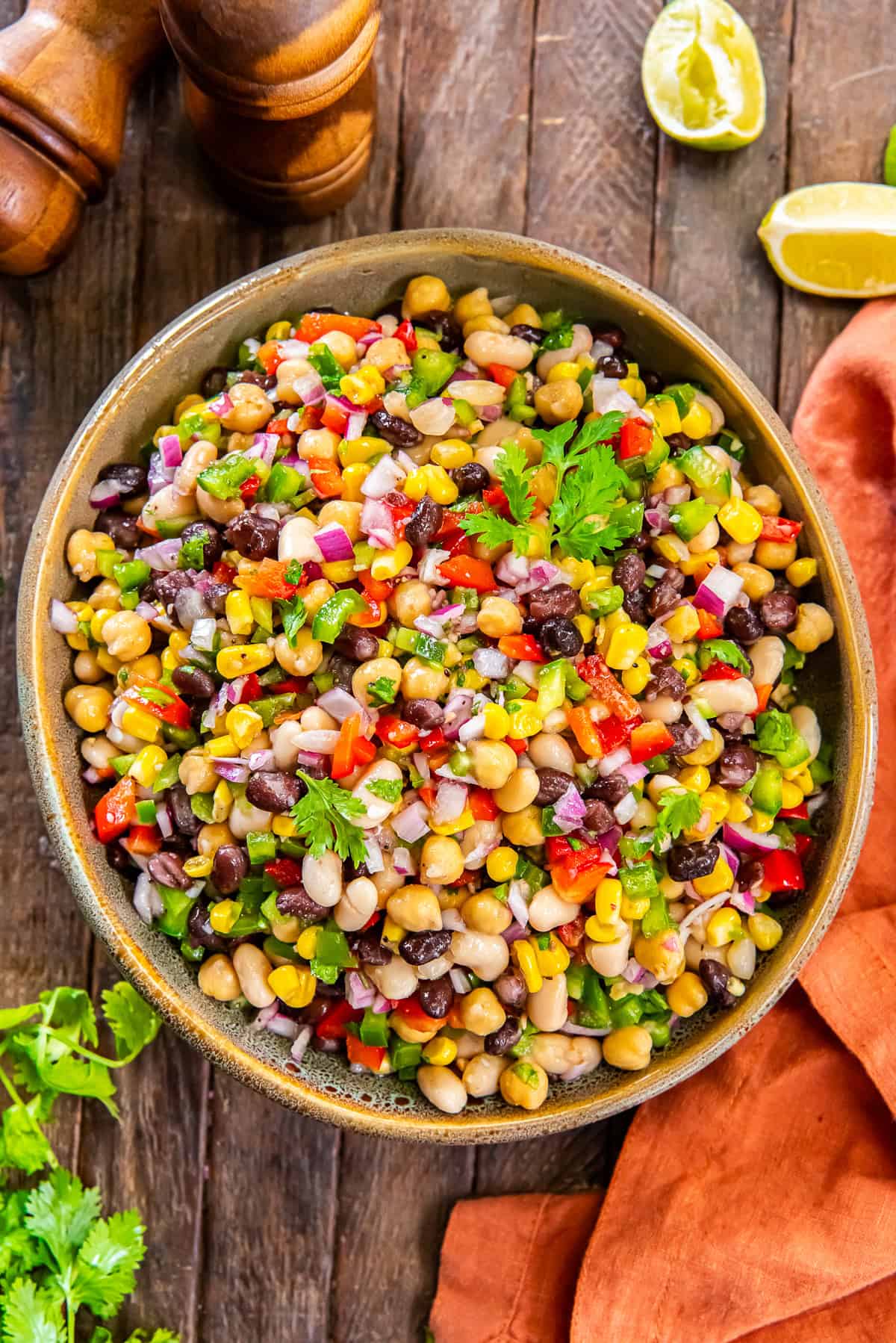 Mexican Bean Salad 2 Mexican bean salad with black beans, white beans, and chickpeas in a large wood bowl next to an orange kitchen cloth.