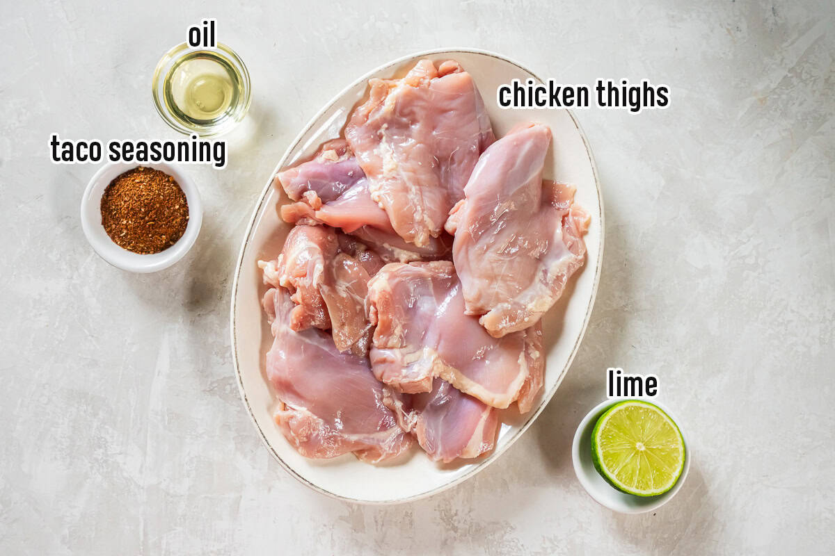 Boneless chicken thighs on a platter surrounded by small bowls of seasoning, oil, and a lime with text overlay.