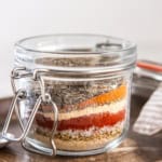 Glass jar filled with layered spices for homemade Cajun seasoning mix.