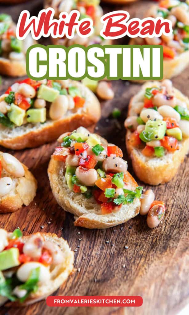 White bean crostini with black eyed peas and avocado on a wood platter with text overlay.