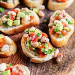 White bean crostini on a wood platter.