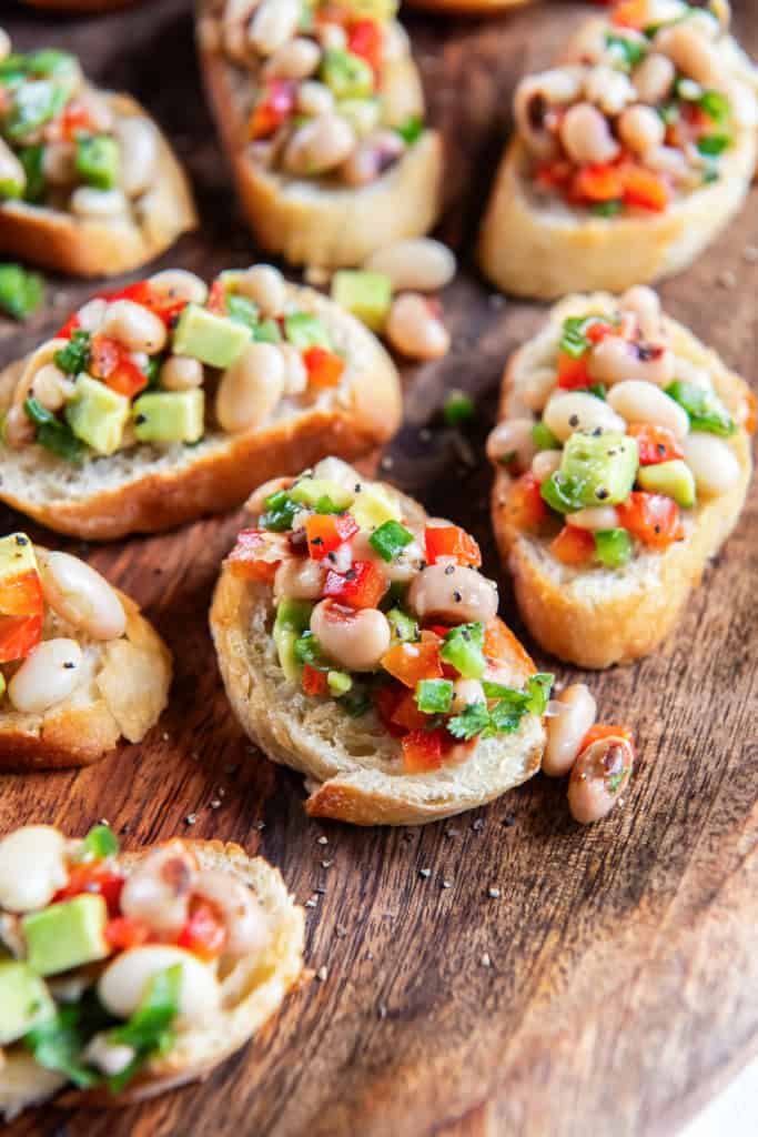 White bean crostini on a wood platter.