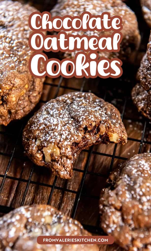 Chocolate oatmeal cookies dusted with powdered sugar on a wire rack with a bite missing from the one in the center with text overlay.