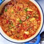 A Dutch oven of Jambalaya Soup with chunks of chicken and sliced sausage.