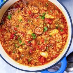 A Dutch oven of Jambalaya Soup with chunks of chicken and sliced sausage.