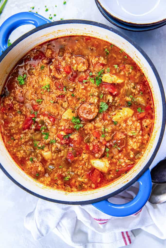 A Dutch oven of Jambalaya Soup with chunks of chicken and sliced sausage.