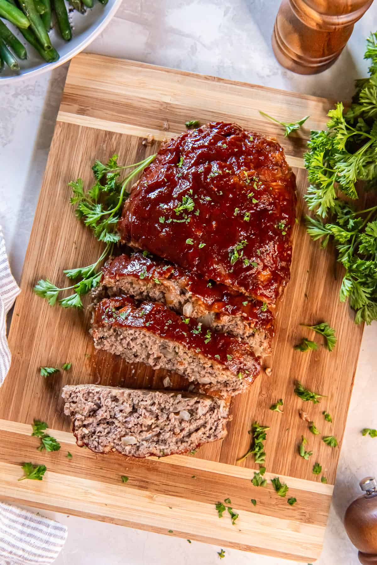 A one pound meatloaf with glaze partially sliced on a cutting board.