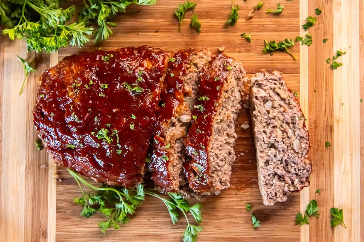 A small one pound meatloaf sliced on a cutting board with parsley.