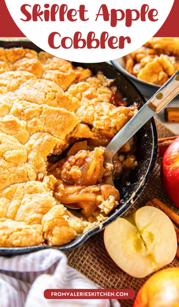 A spoon resting in apple cobbler in a skillet with text overlay.