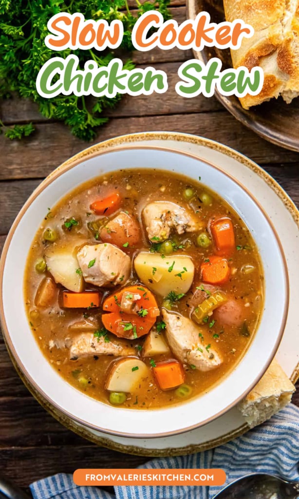 Chicken stew with carrots, red potatoes, peas, and parsley in a white bowl on a rustic table with bread with text overlay.