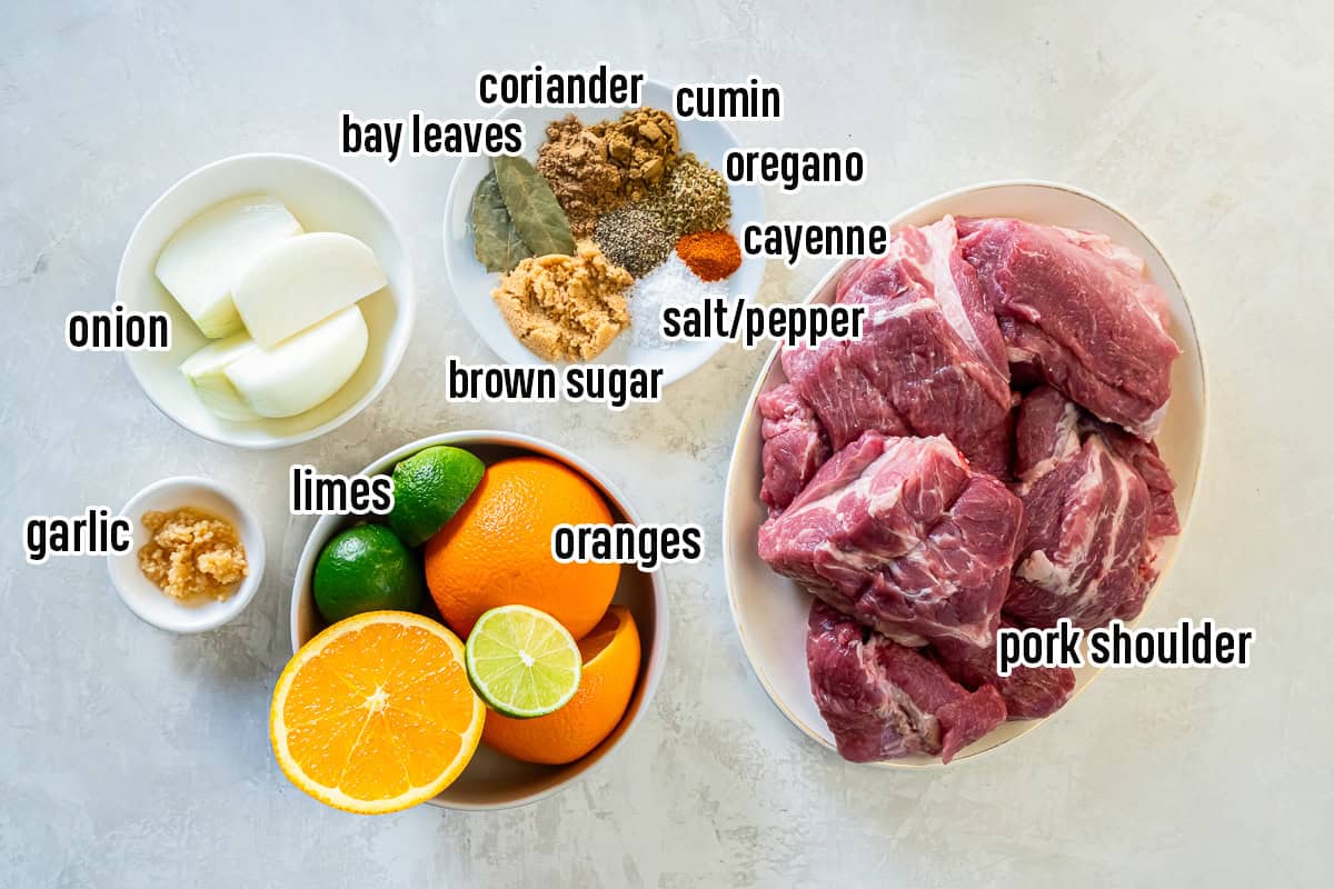 Carnitas ingredients including chunks of pork shoulder roast, onion, garlic, oranges, limes, and spices with text overlay.