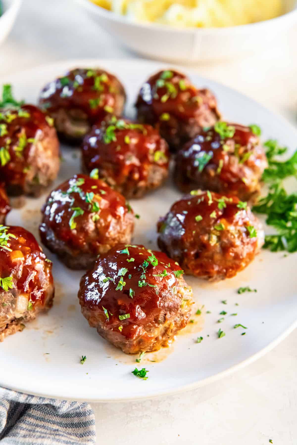 Glazed meatloaf muffins in a circular pattern on a white plate.