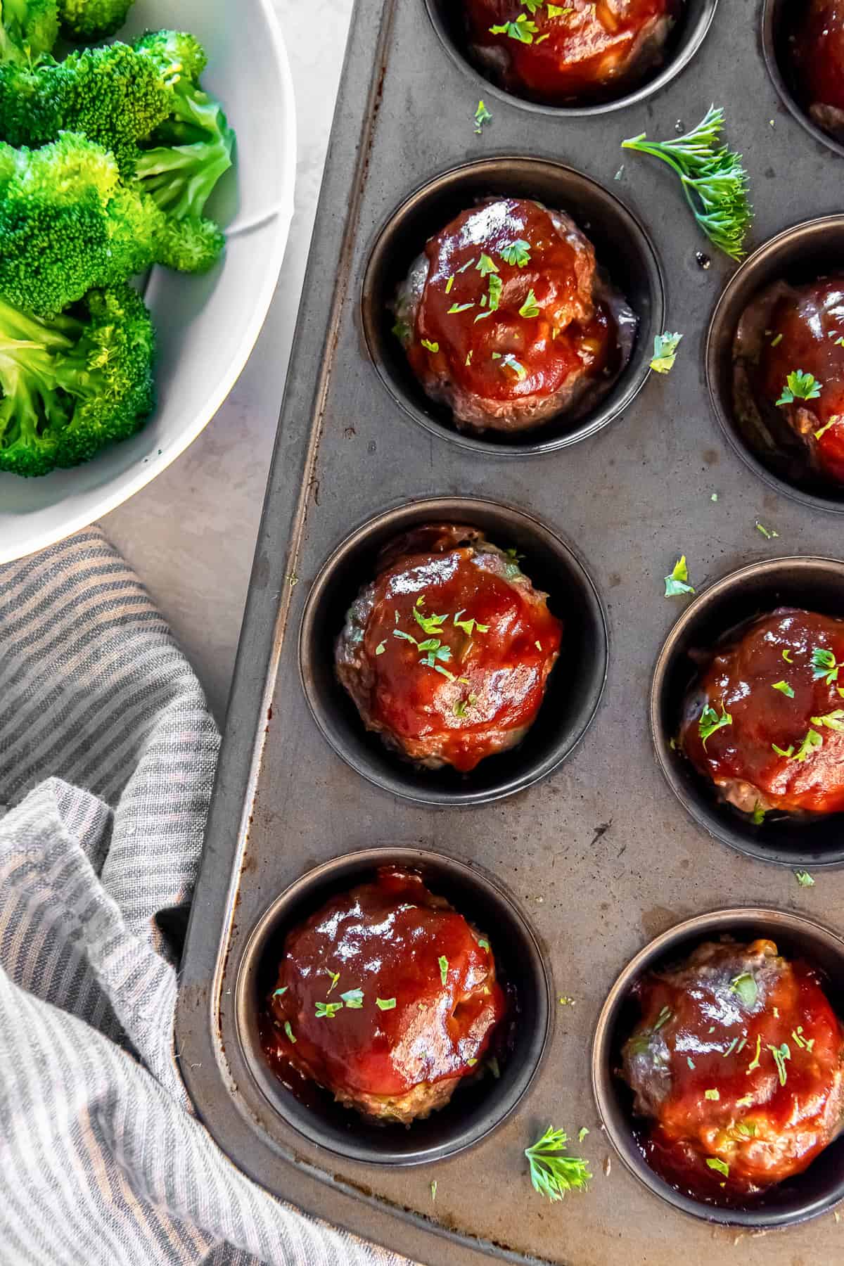 Glazed meatloaf muffins in a muffin pan topped with chopped parsley