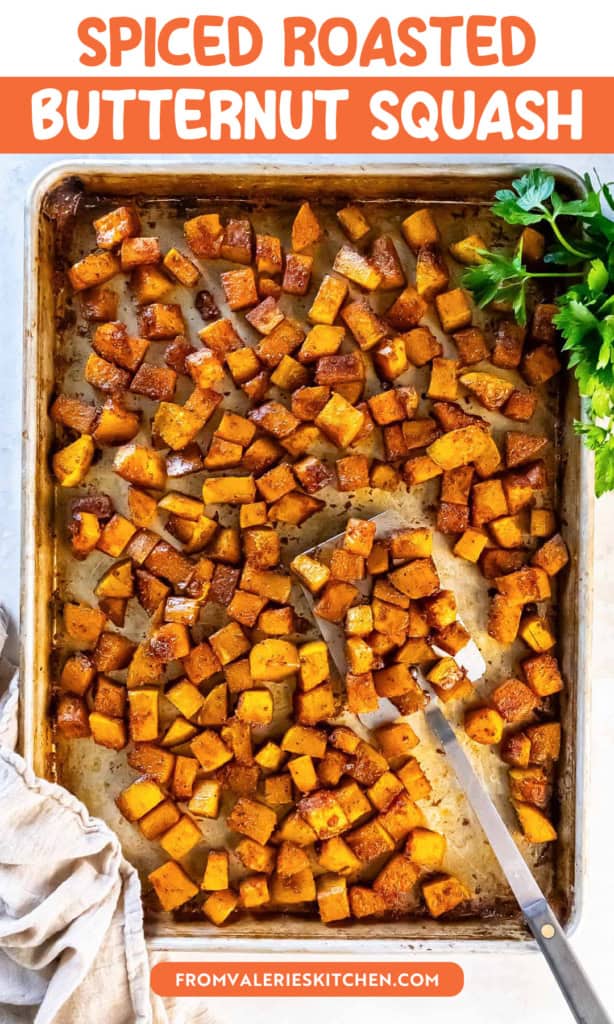 Roasted butternut squash cubes on a sheet pan with a spatula and parsley with text overlay.