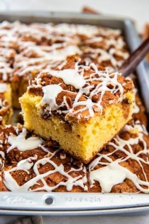 Slice of cake mix coffee cake lifted from the pan, topped with chopped pecans and a drizzle of white icing.