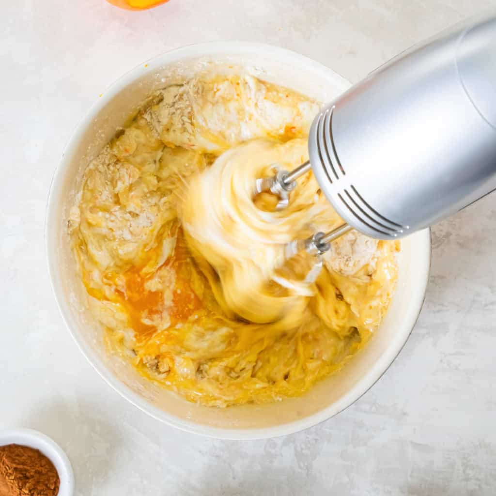 Wet ingredients being combined with an electric mixer in a bowl.