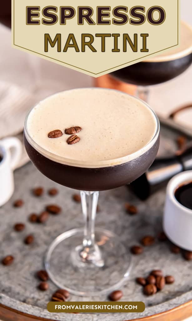 A chilled espresso martini in a coupe glass topped with a thick layer of creamy foam and three coffee beans, set on a metal tray with scattered coffee beans, small espresso cups, and a cocktail jigger in the background with title text overlay.