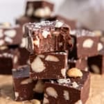 Close-up of stacked macadamia nut fudge with a bite taken out of the top piece.