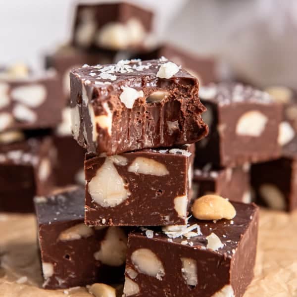Close-up of stacked macadamia nut fudge with a bite taken out of the top piece.