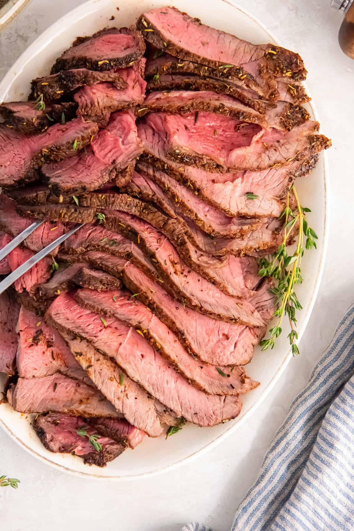 Air fryer sirloin tip roast sliced thin and arranged on a serving platter, cooked to medium-rare.