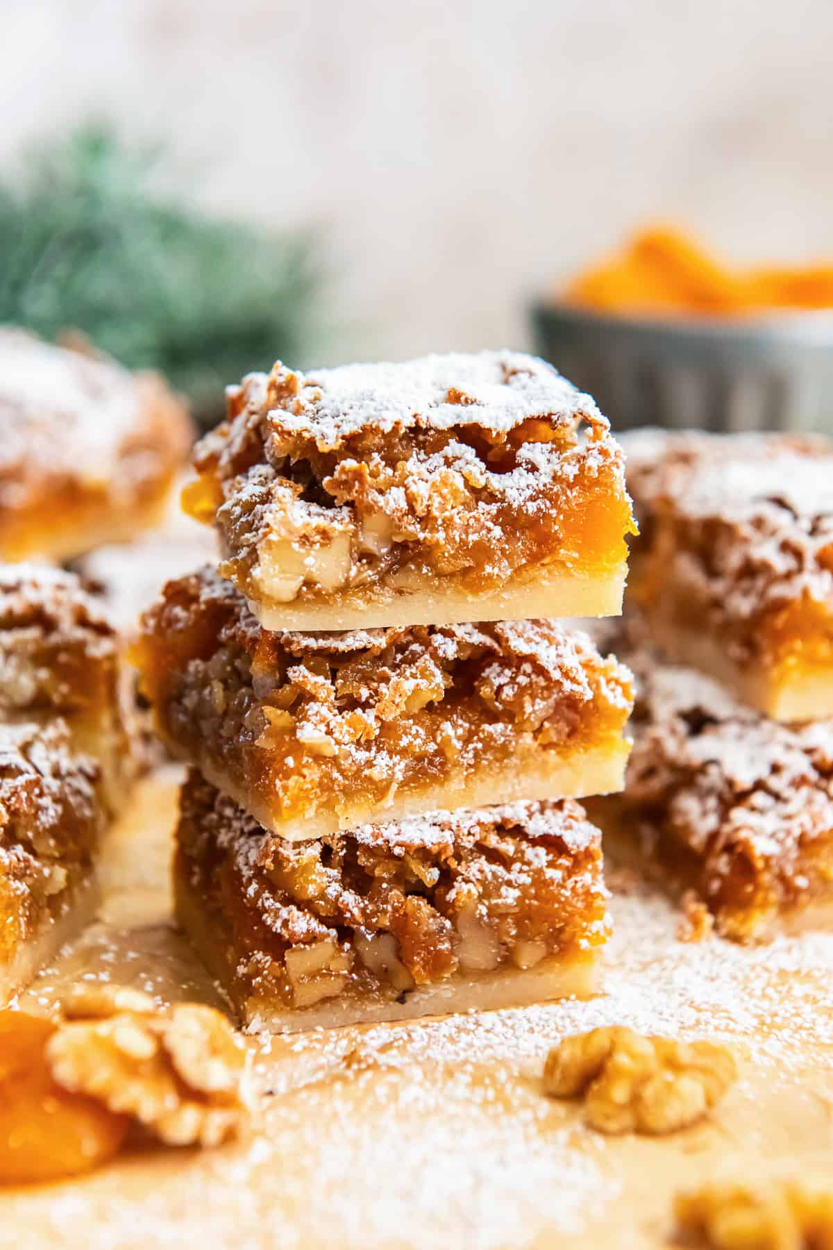 Stacked apricot bars showing the buttery shortbread crust and chewy apricot-walnut filling, dusted with powdered sugar.