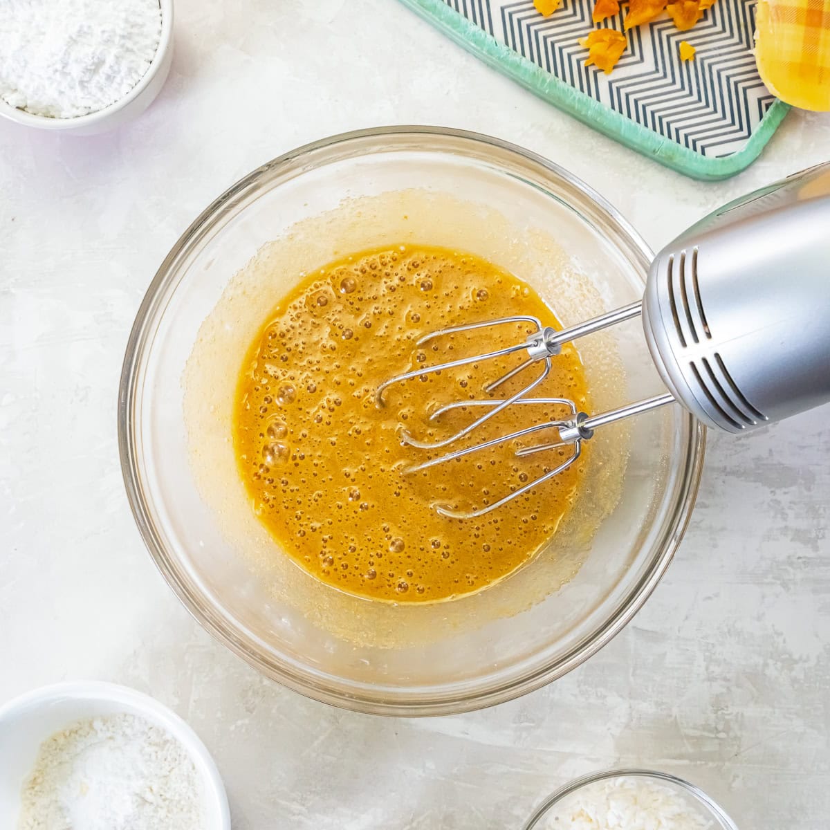 Eggs, brown sugar, and vanilla being mixed with an electric hand mixer.