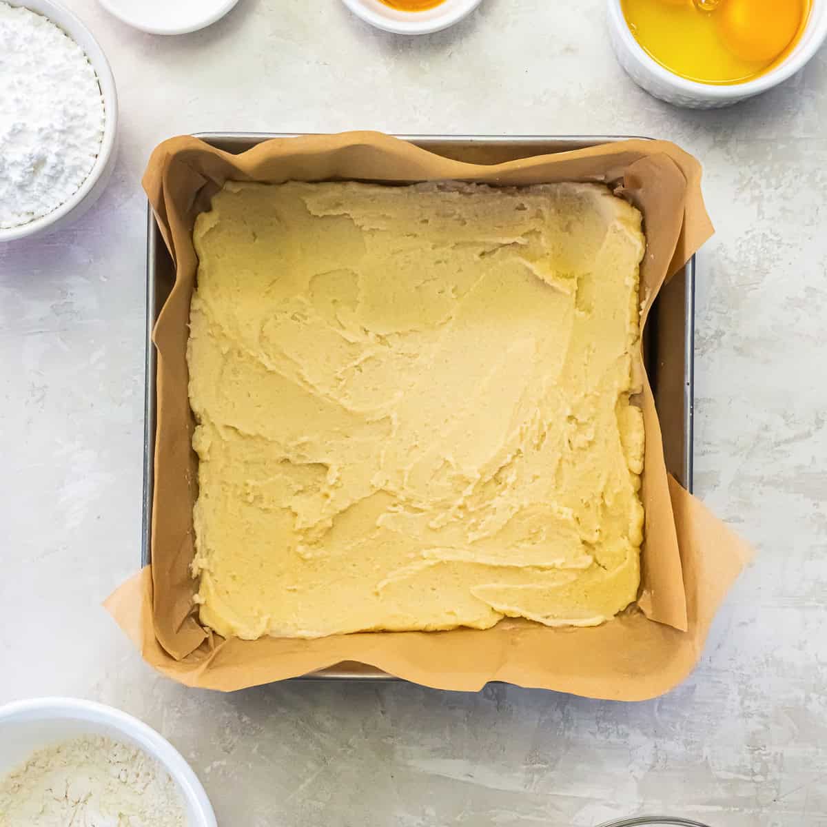 Shortbread-style crust pressed into a parchment-lined square baking pan.