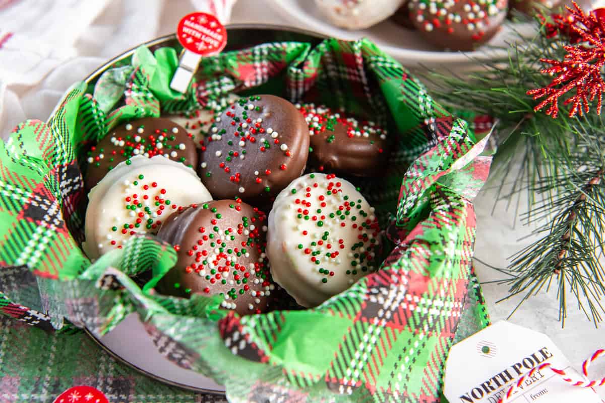 Tin lined with plaid holiday tissue filled with chocolate- and white-chocolate–dipped peanut butter Ritz cookies topped with red, green, and white sprinkles.