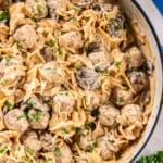 Creamy Meatball Stroganoff with wide egg noodles, mushrooms, and meatballs in a skillet, sprinkled with chopped parsley.