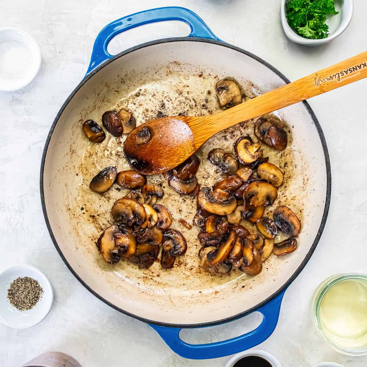Sliced cremini mushrooms browning in butter in the skillet.