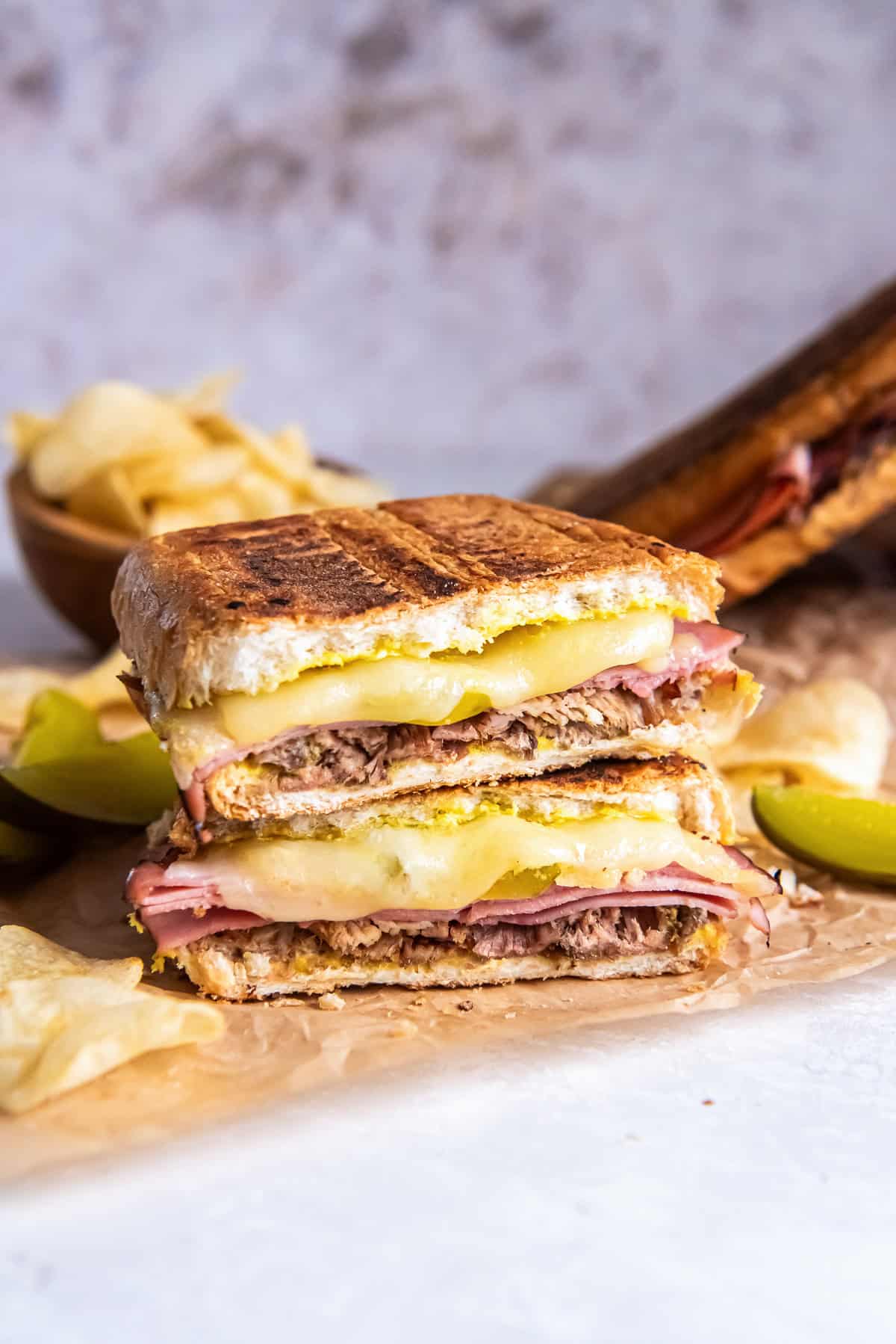 A pressed Cuban sandwich showing layers of roast pork, ham, melted Swiss cheese, pickles, and mustard on golden toasted bread.