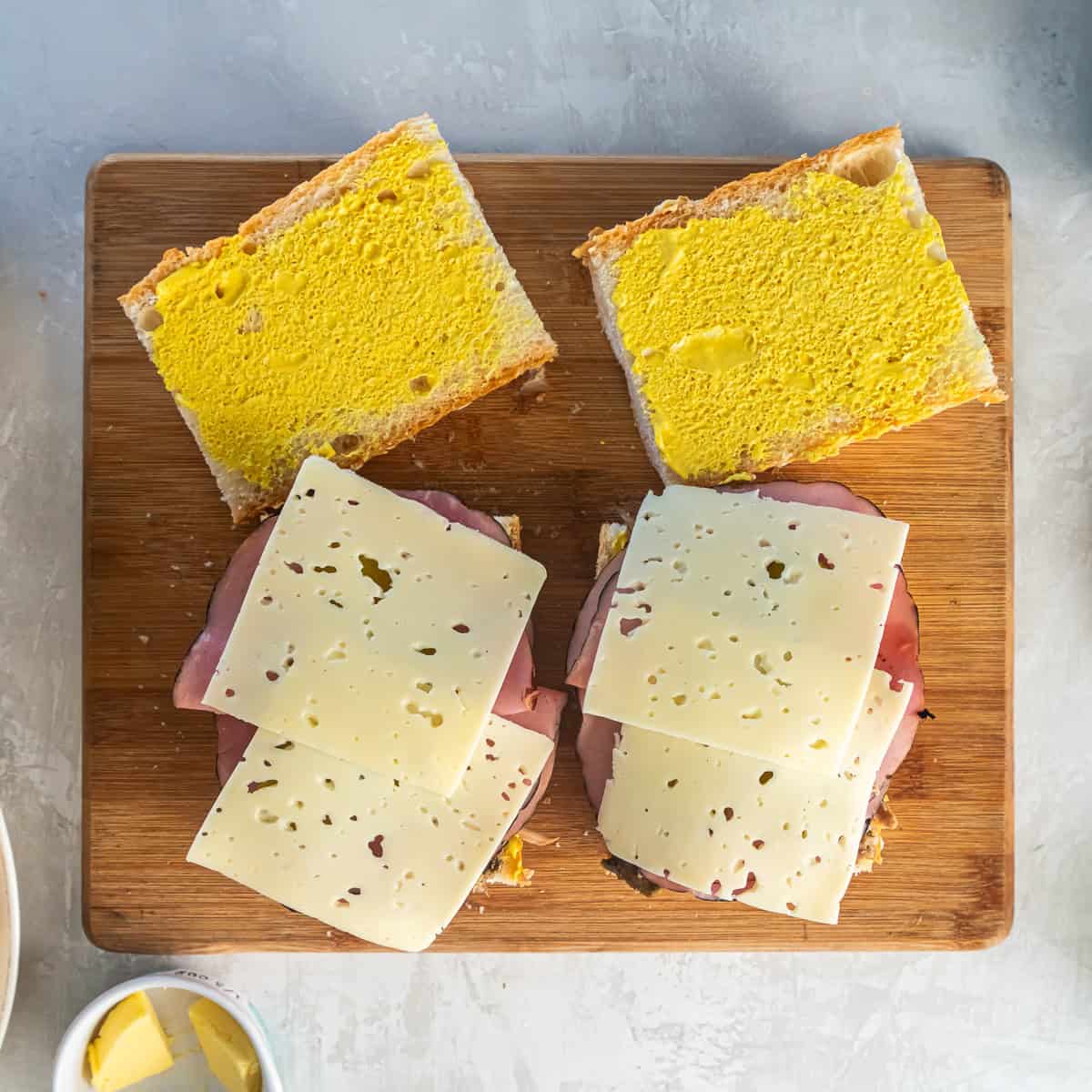 Swiss cheese slices layered over deli ham on Cuban bread for Cuban sandwiches.