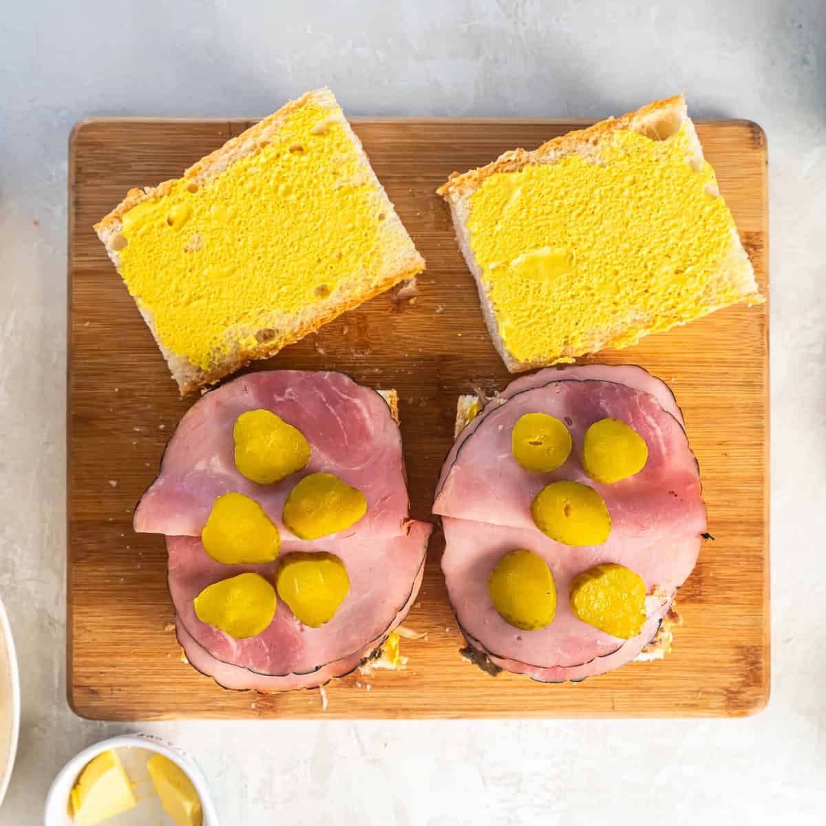 Dill pickle chips layered over ham and cheese on Cuban sandwich bread.