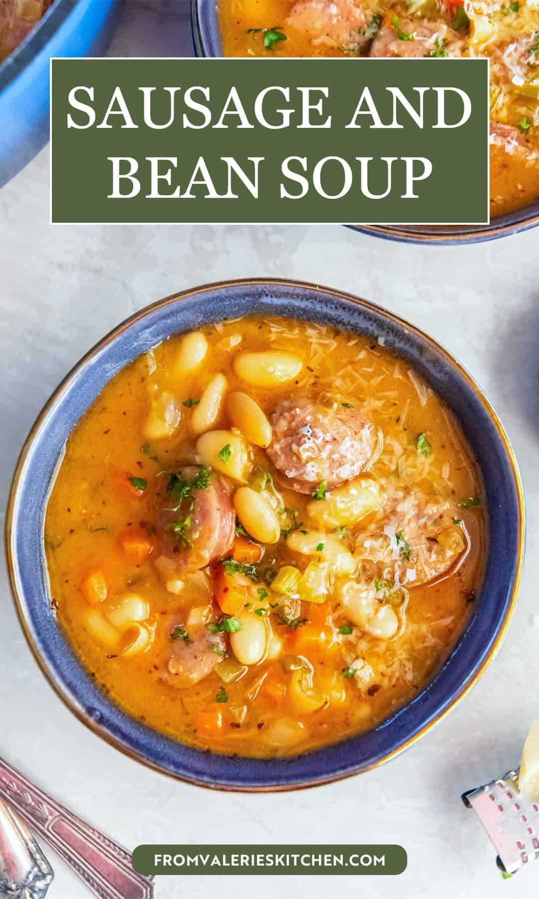 Bowl of sausage and bean soup with white beans, sliced sausage, carrots, celery, and a hearty, savory broth with text overlay.
