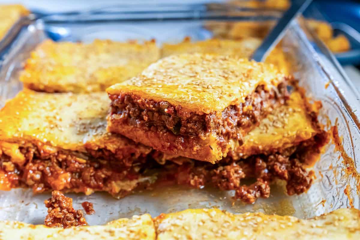 Sloppy Joe Squares baked in a glass dish with one square lifted to show the layers of crescent dough crust and savory ground beef filling.