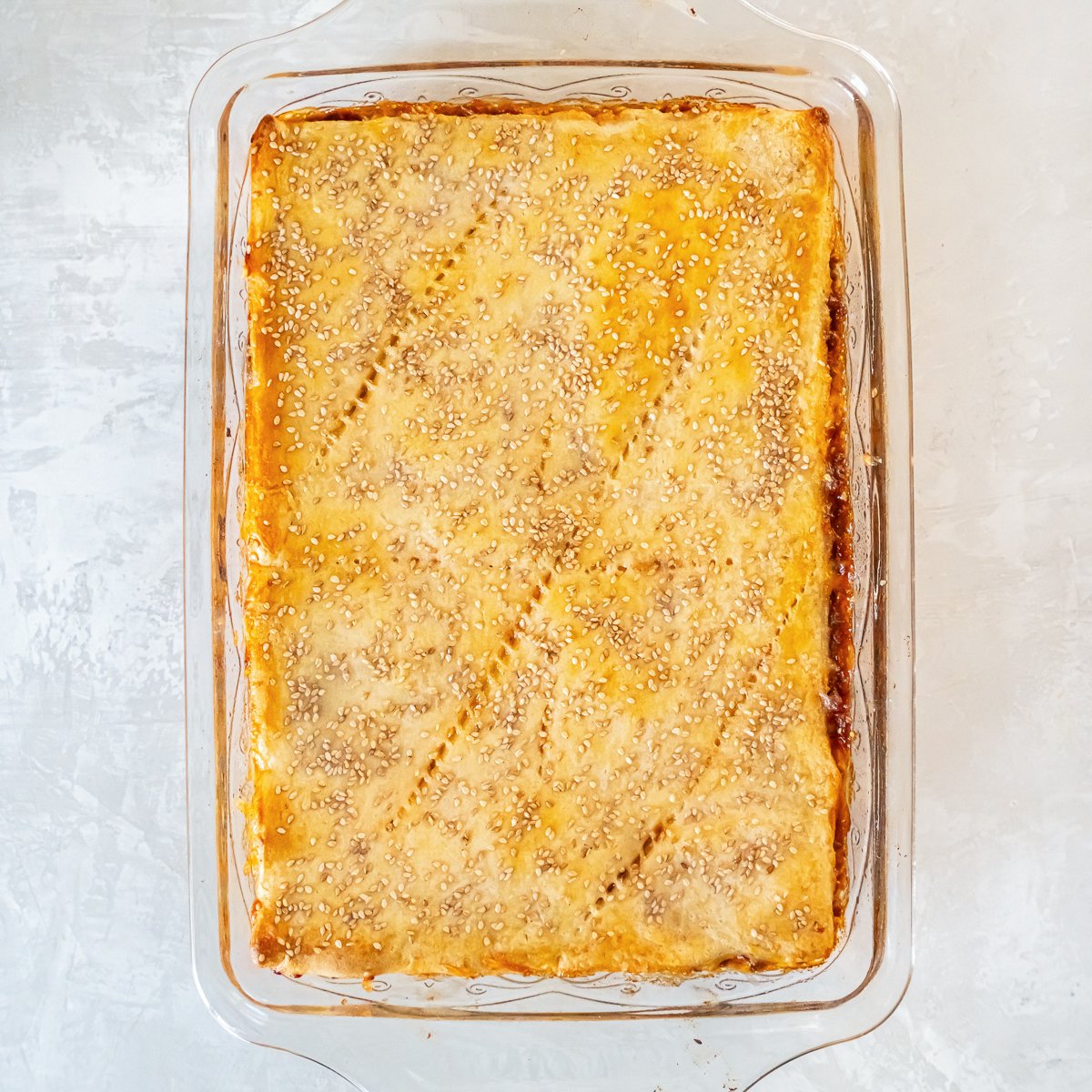 Baked Sloppy Joe Squares with a golden brown crescent roll crust and sesame seeds on top, fresh from the oven.