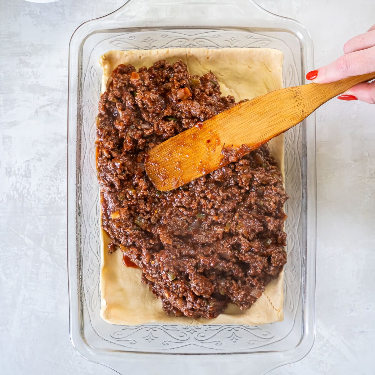 Sloppy Joe filling spread evenly over the crescent roll dough in the baking dish.