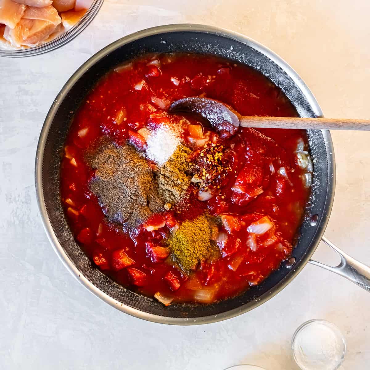 Tomato sauce, diced tomatoes, onions, and spices in a skillet before stirring to make the tikka masala base.