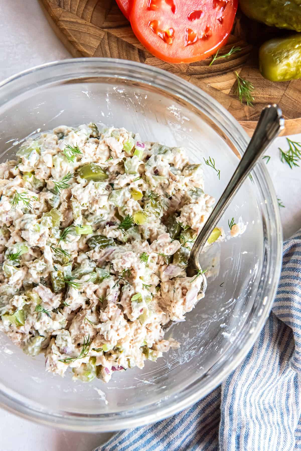 Dill pickle tuna salad in a glass bowl with visible chunks of albacore tuna, pickles, celery, and fresh dill.