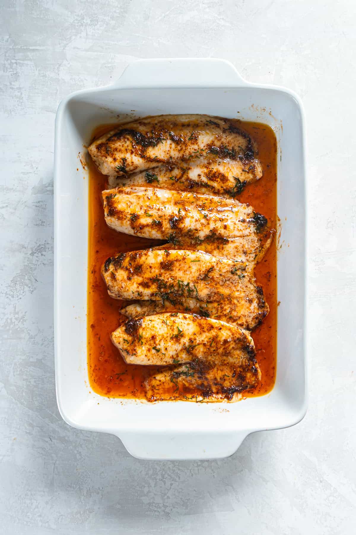 Easy baked fish fillets finished in a baking dish with melted butter sauce.