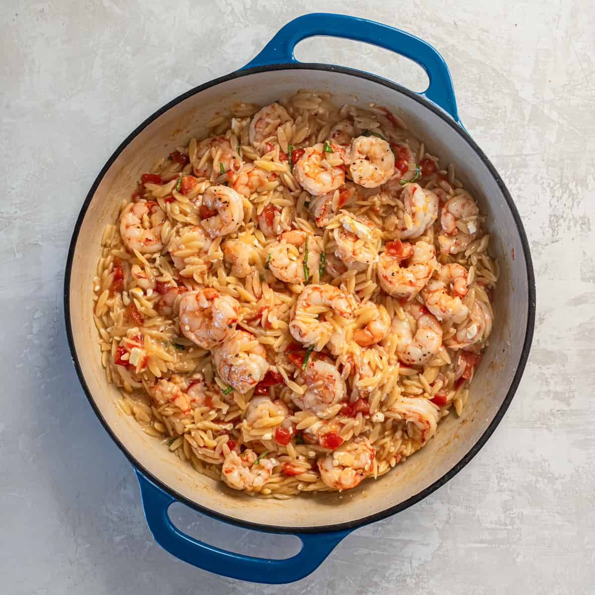 Finished orzo pasta with shrimp, tomatoes, and feta served in a skillet.
